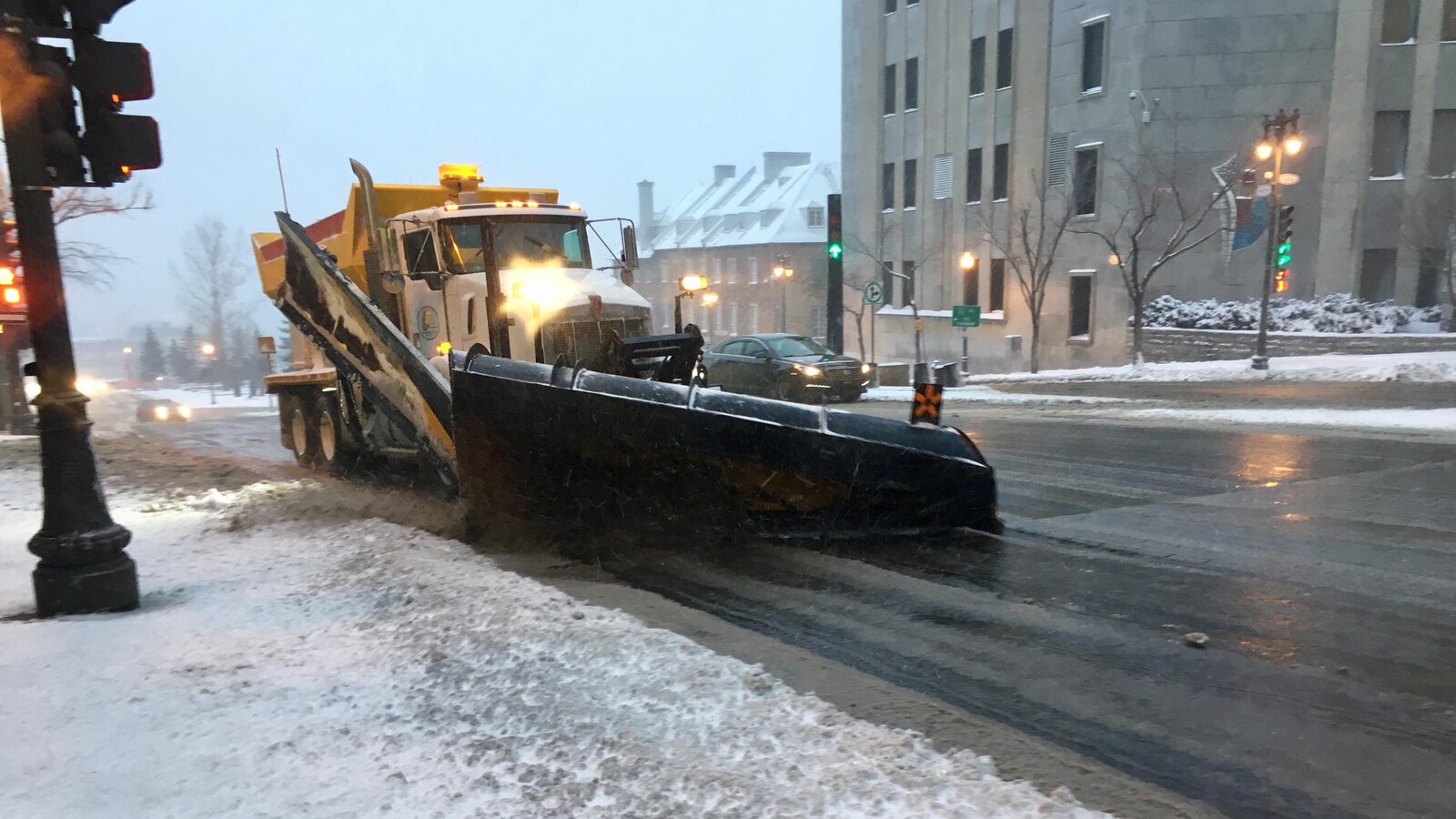 Un chasse-neige dégage une rue en plus d'épandre des abrasifs.