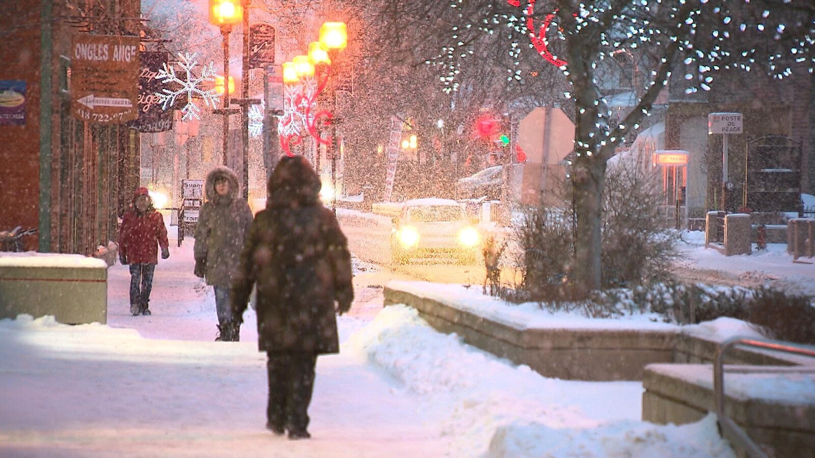 Des piétons marchent sous la neige au centre-ville de Rimouski.