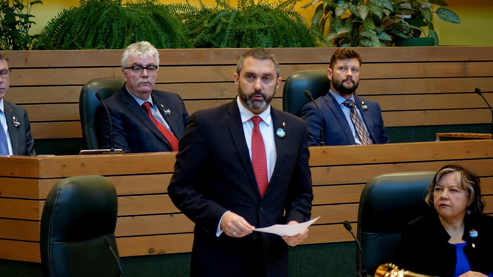 Un homme debout entouré d'autres personnes siégeant dans un parlement.
