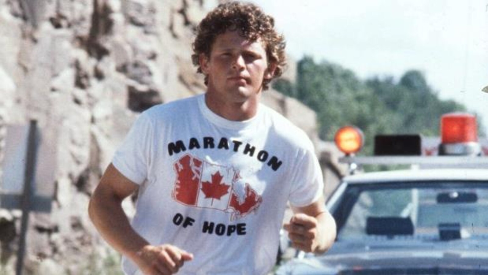 Terry Fox court avec un chandail inscrit marathon de l'espoir en anglais (marathon of hope).