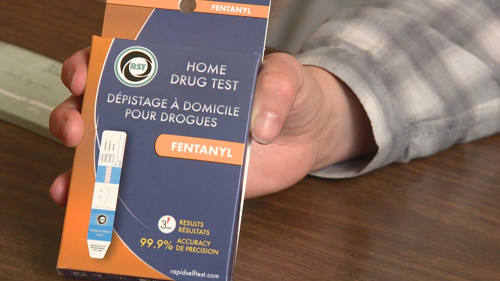 Une main tient la boite où il est écrit « dépistage à domicile pour drogues ».