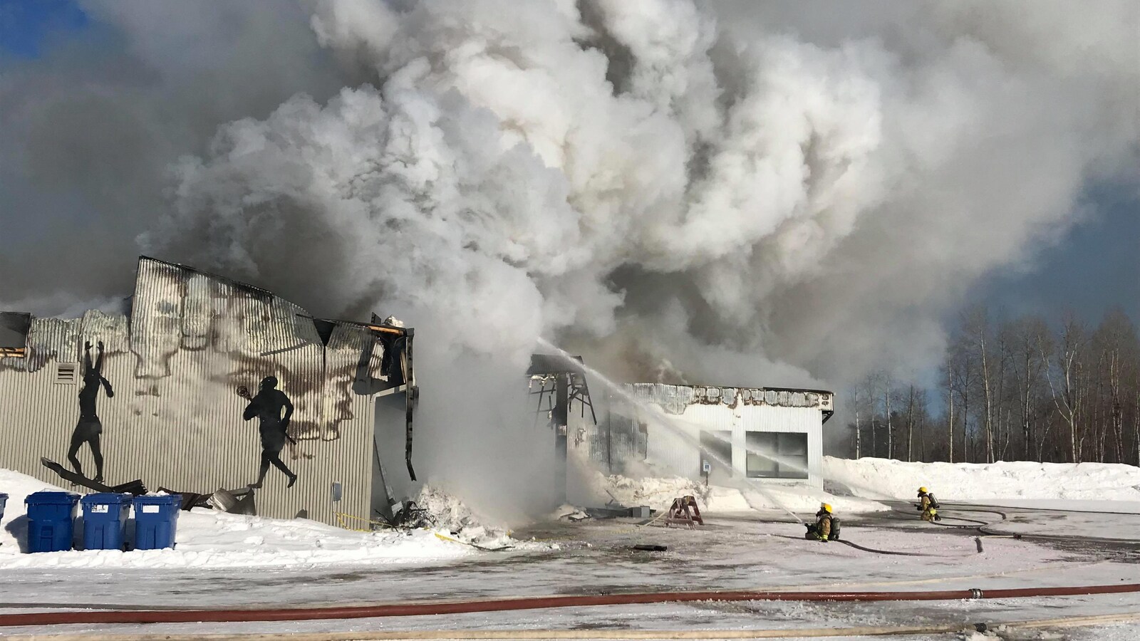 Des pompiers agenouillés dans la neige tente d'éteindre l'incendie.