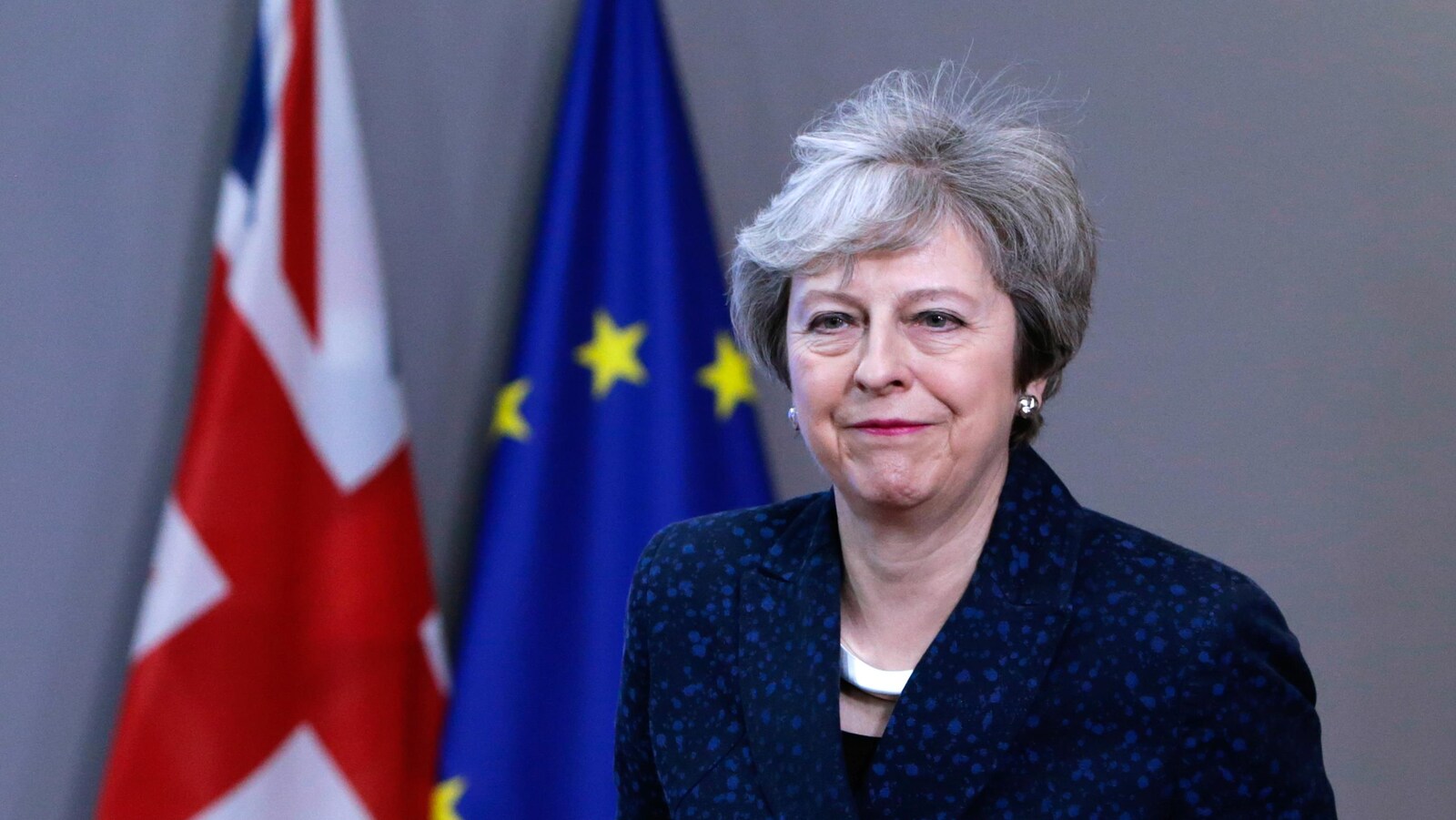 Une femme regarde devant elle alors qu'elle passe devant un drapeau britannique et un drapeau européen.
