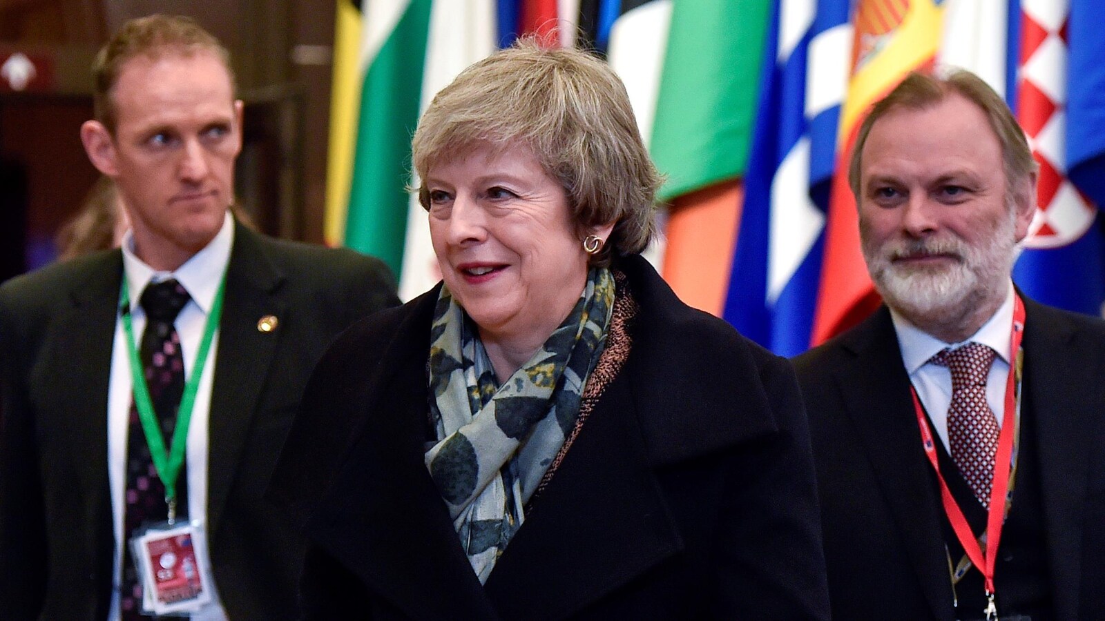 Mme May devance un peu Tim Barrow, devant les drapeaux des pays de l'Union européenne.
