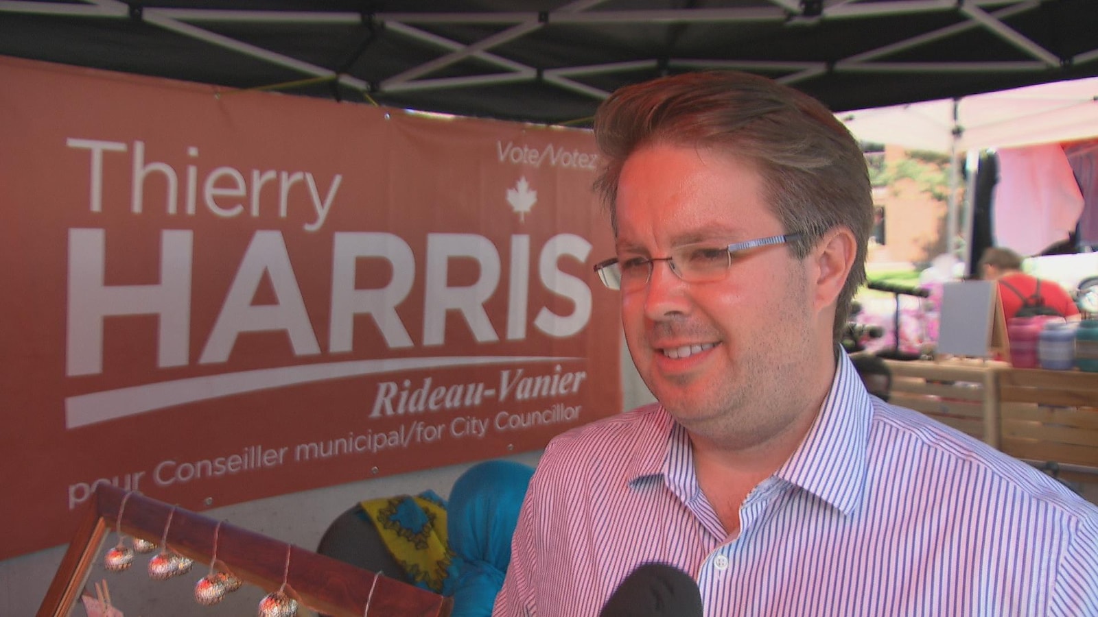 Le candidat au poste de conseiller municipal du quartier Rideau-Vanier, Thierry Harris, en entrevue sous un kiosque avec une pancarte électorale portant son nom