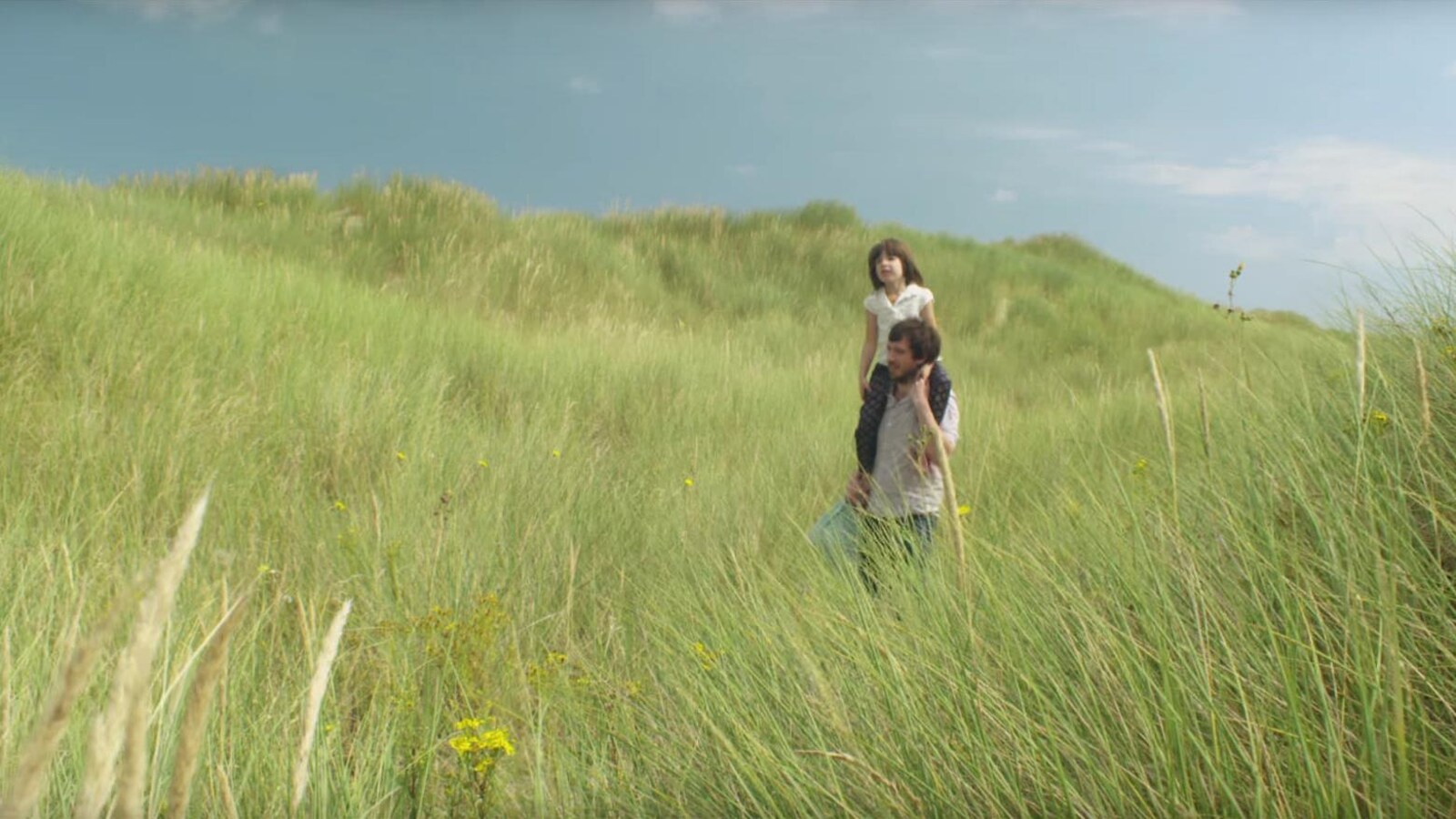Thomas Blanchard porte Lina Doillon sur ses épaules dans un grand champ dans une scène du film «Drôle de père».