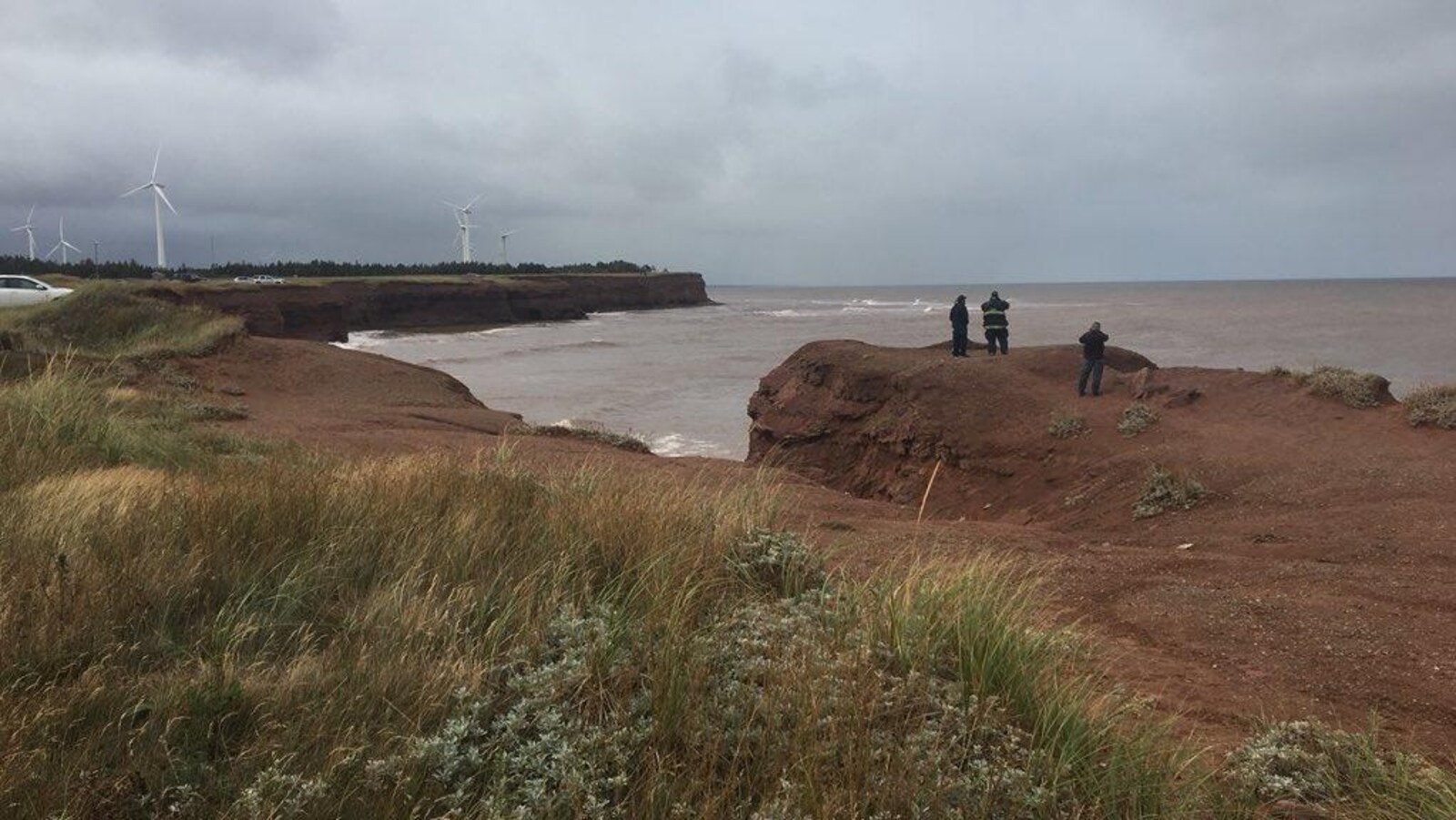 Trois personnes sur la côte regardent vers la mer