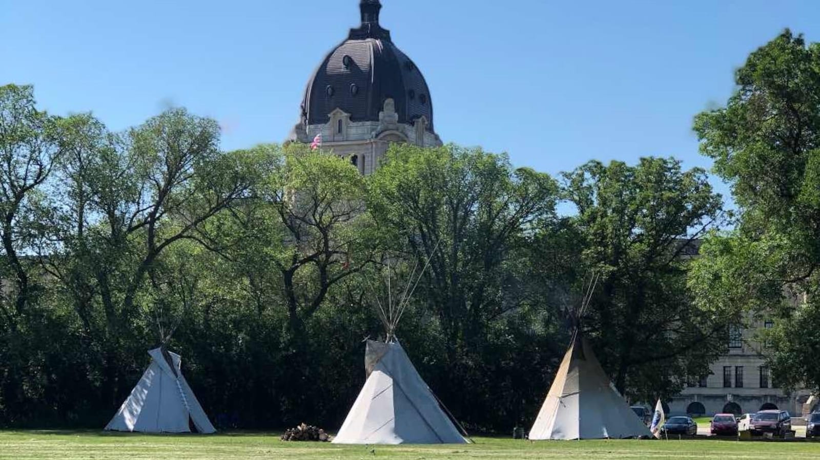 Trois tipis un à côté de l'autre dans le parc Wascana en face de l'Assemblée législative de la Saskatchewan.