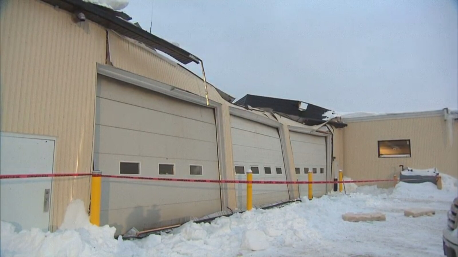 Le toit d'un garage effondré au dessus de trois portes de garage.