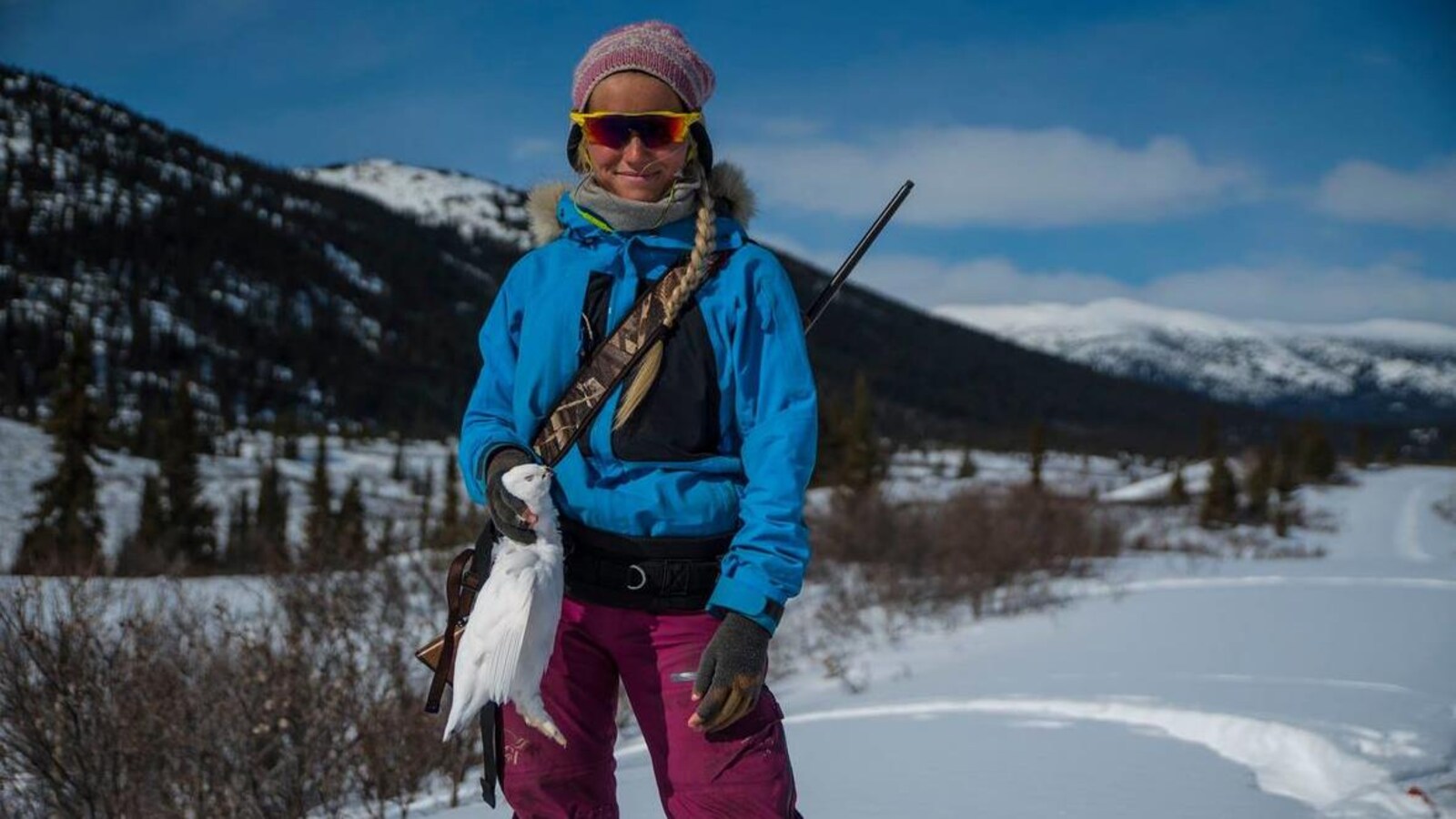 Une femme debout dans la neige avec un oiseau blanc dans la main.