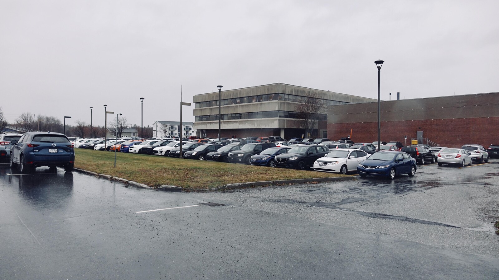 Le stationnement de l'édifice René-Tremblay rempli de véhicules stationnés.