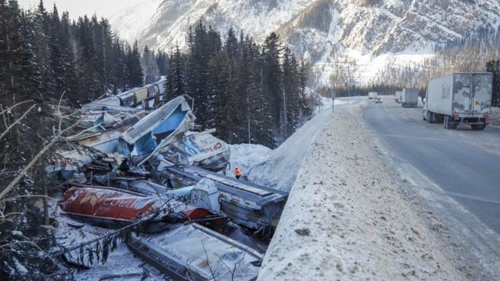 Une dizaine de wagons brisés sont empilés sur le bord d'une route enneigée.
