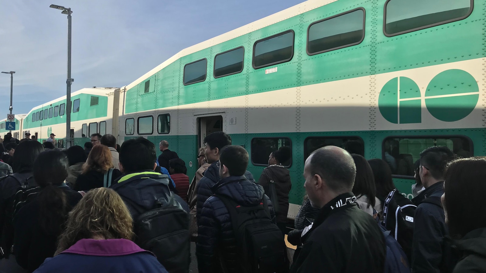 Photo de passagers massés près d'un train vert et blanc