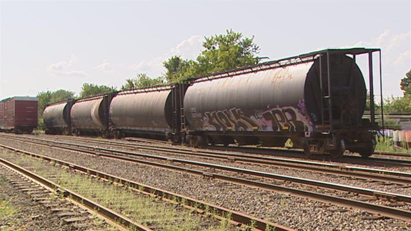 Une voie ferrée où sont garés des wagons citernes et de marchandises.