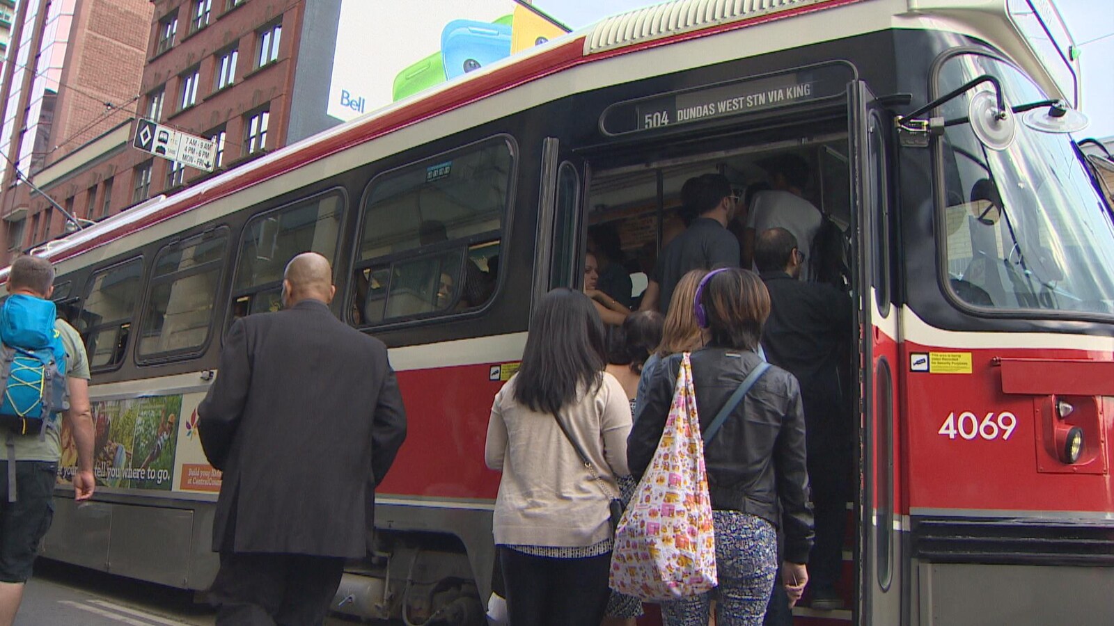 Des usagers tentent de monter à bord d'un tramway qui est bondé.
