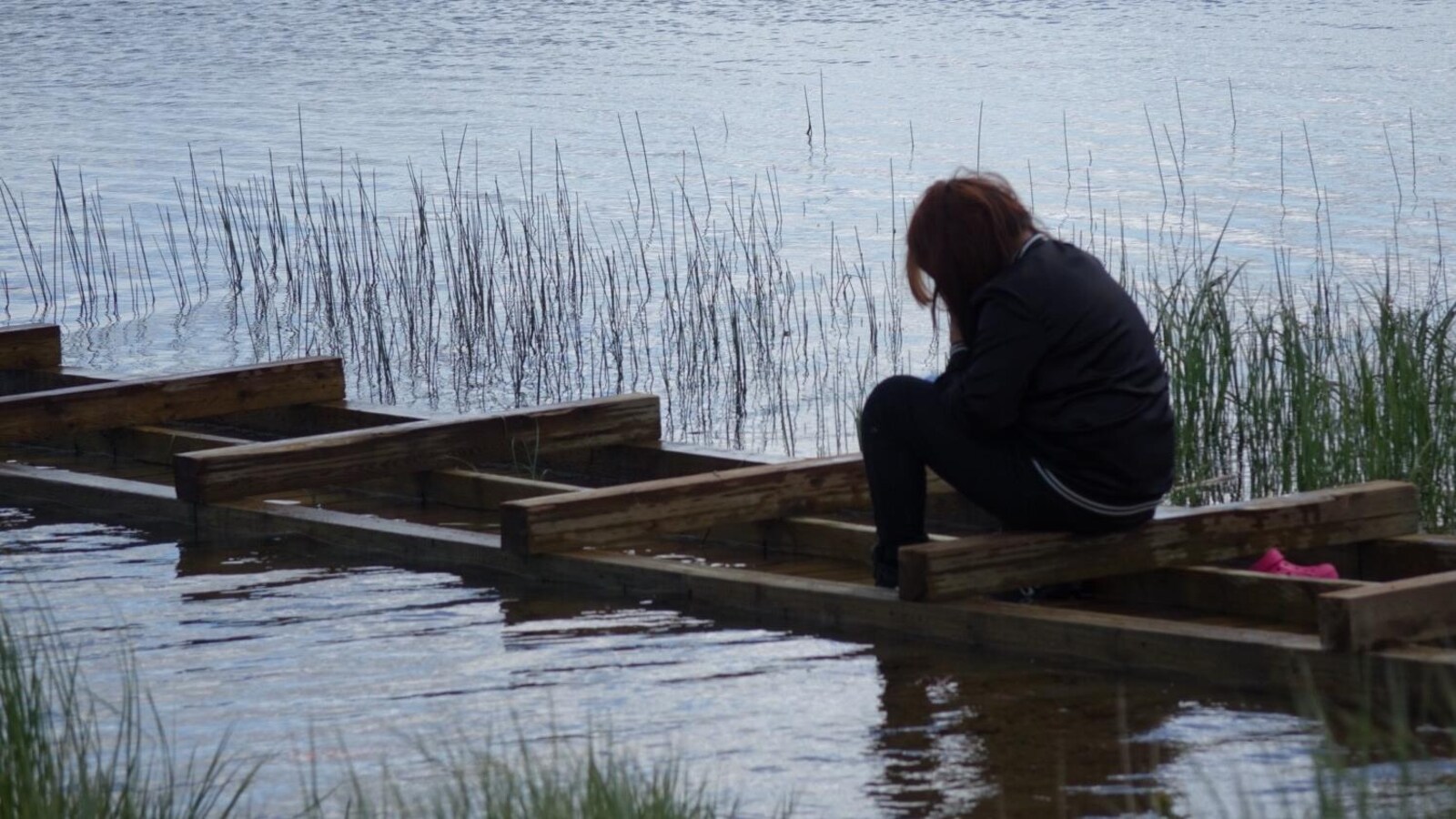 Une adolescente est assise seule sur un quai