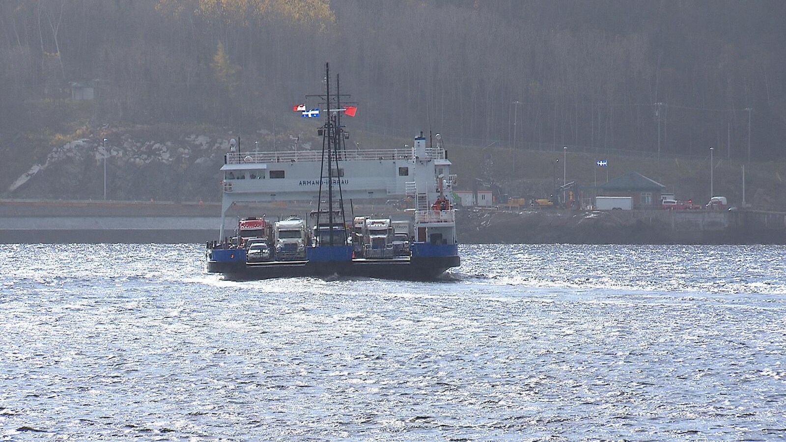 Un traversier flotte sur l'eau et semble rempli de véhicules lourds.