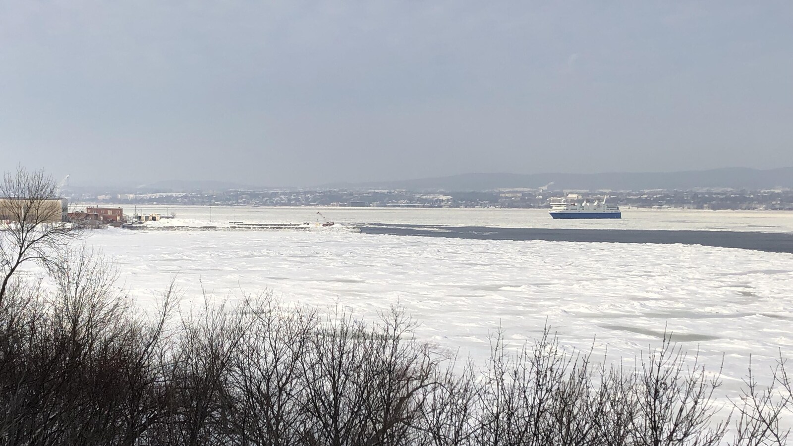 Vu de loin, le navire avance sur l'eau glacée.