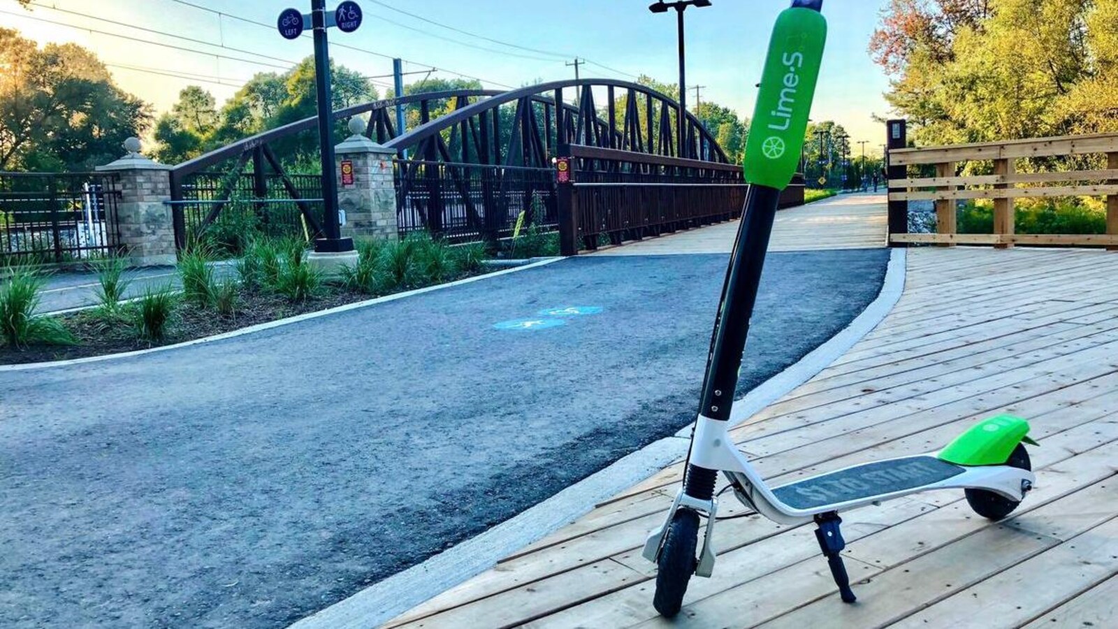 Photo d'une trottinette noire et verte stationnée sur un plancher de bois.