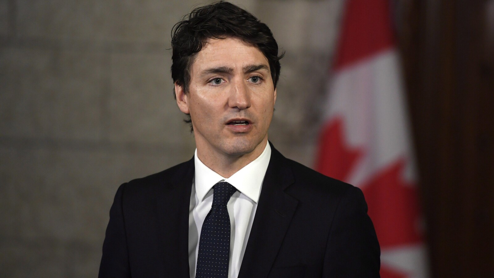 Le premier ministre Justin Trudeau devant un drapeau du Canada.