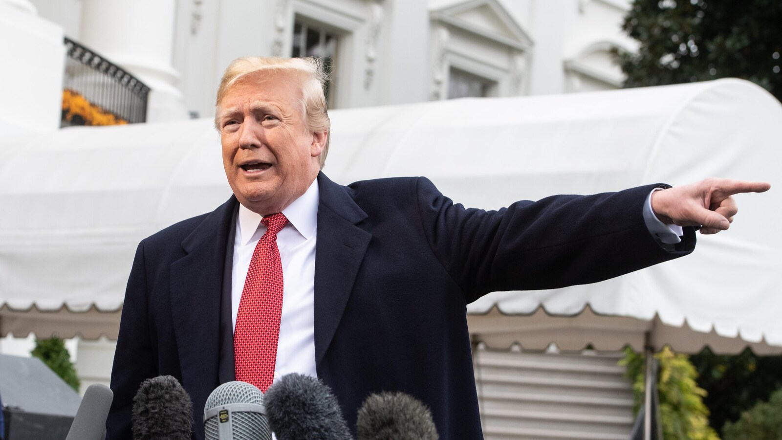 Le président américain Donald Trump pointe quelque chose du doigt en parlant à des journalistes sur la pelouse de la Maison-Blanche, à Washington.