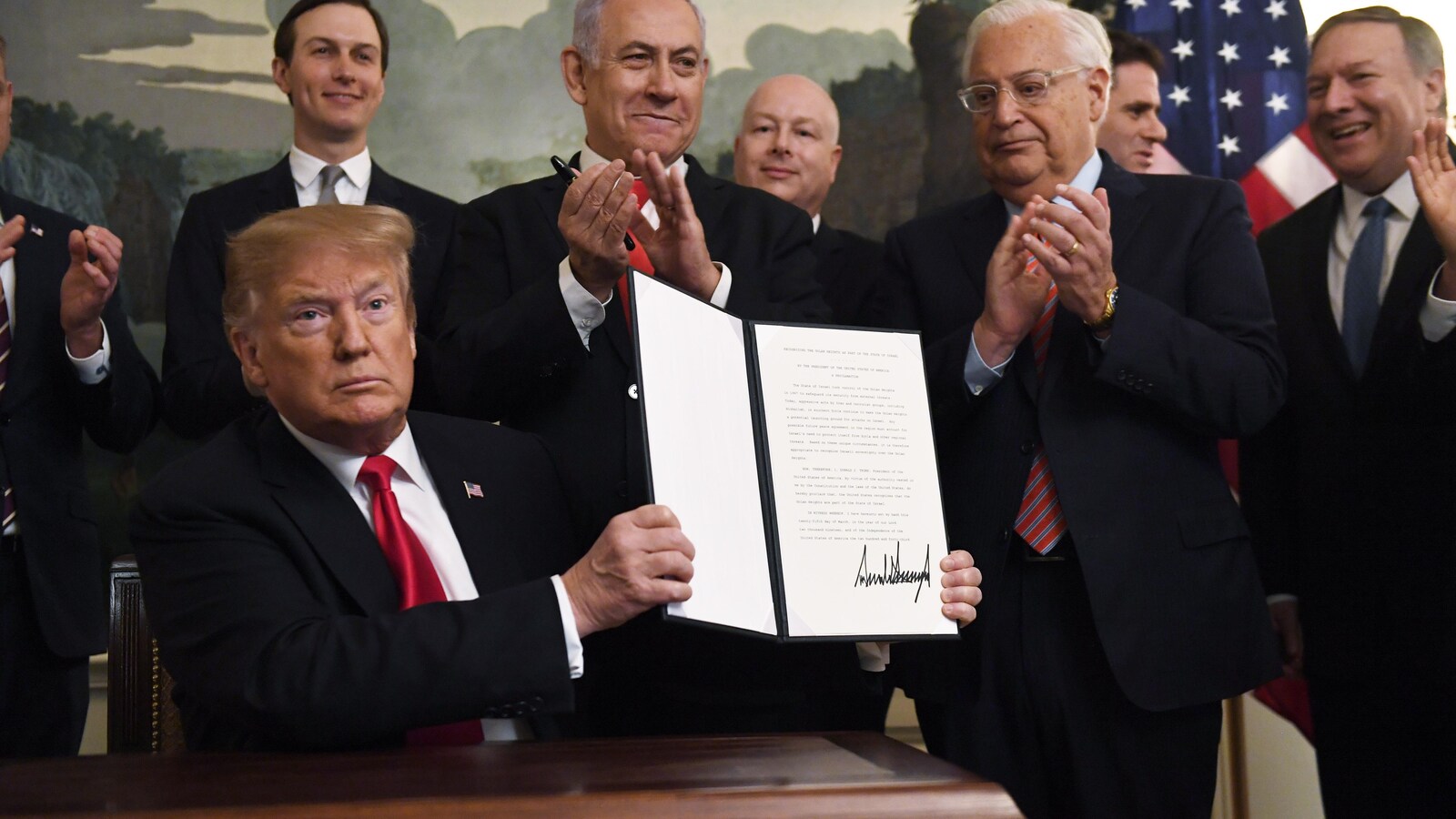 Le président Trump exhibe le décret signé. Derrière lui, on peut notamment apercevoir son conseiller et gendre Jared Kushner et le premier ministre israélien Benyamin Nétanyahou.