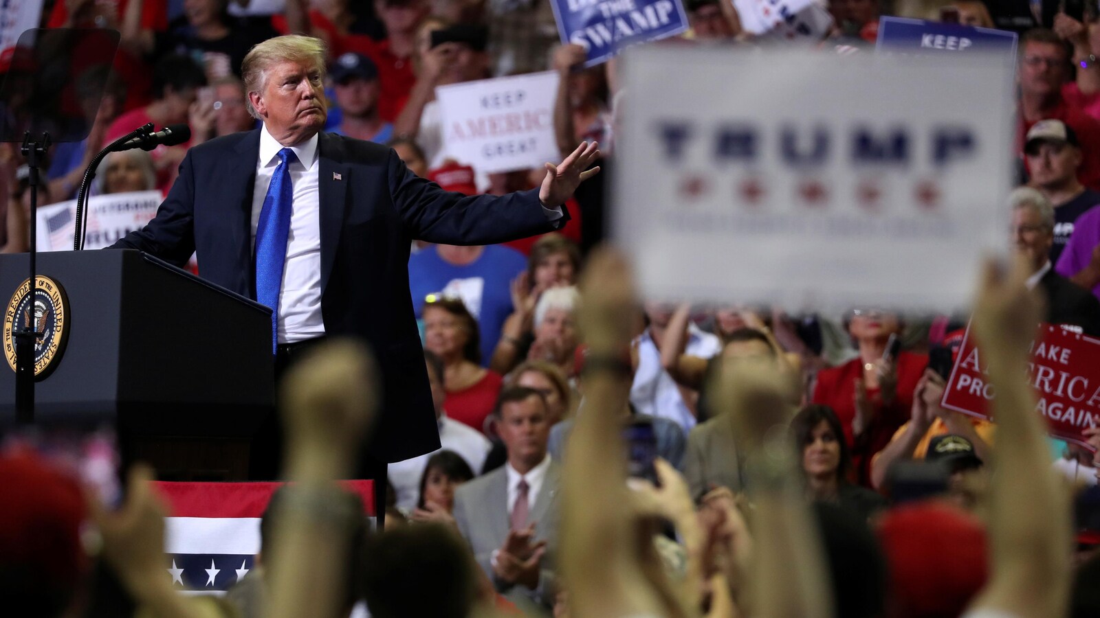 Le président Donald Trump se tourne vers des partisans au cours d'un rassemblement politique à Southaven, au Mississippi, alors que plusieurs d'entre eux brandissent des pancartes.