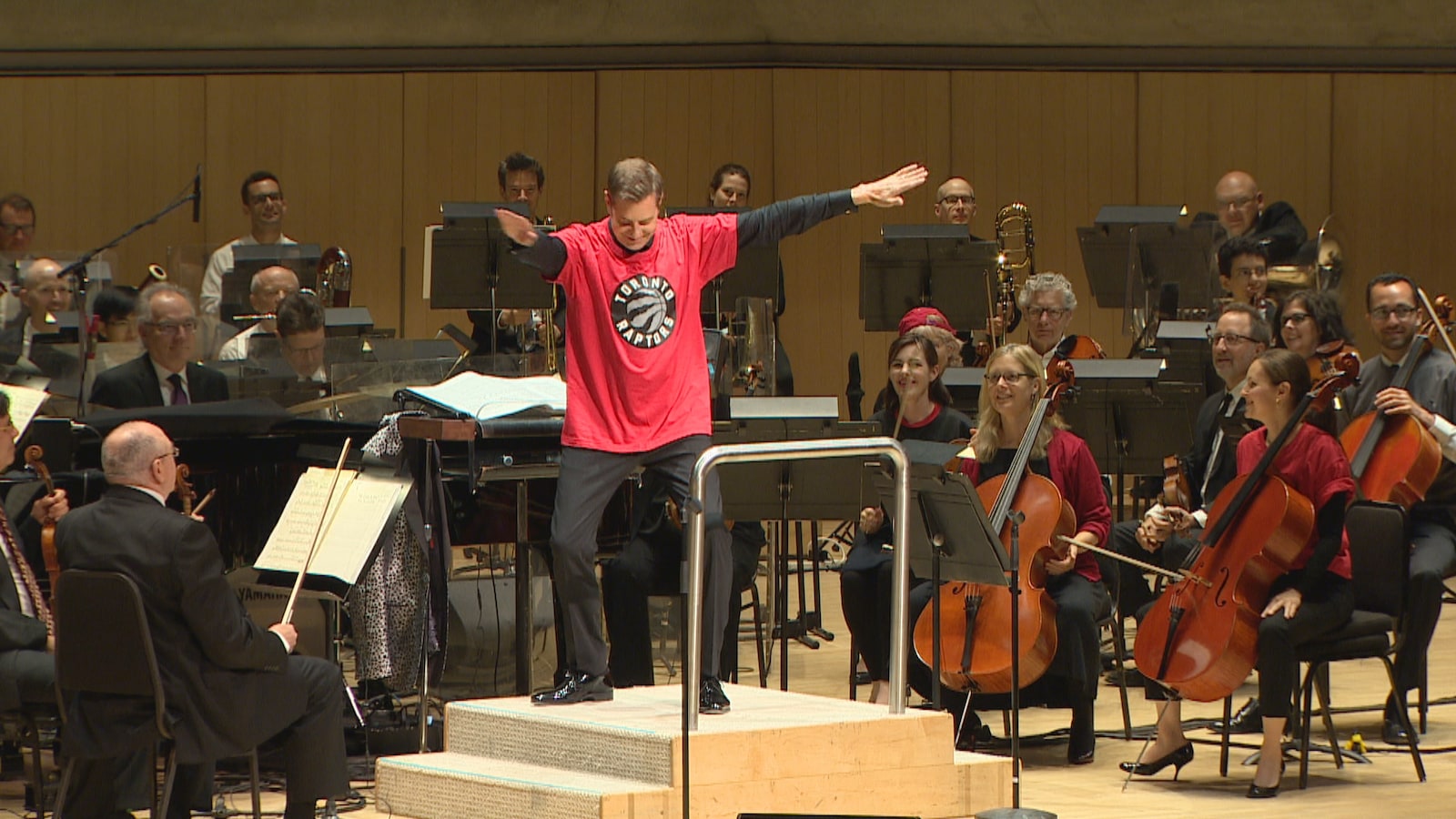 Le chef d’orchestre Steven Reineke sur la scène du Roy Thomson Hall, entouré par les membres de l'Ochestre symphonique de Toronto