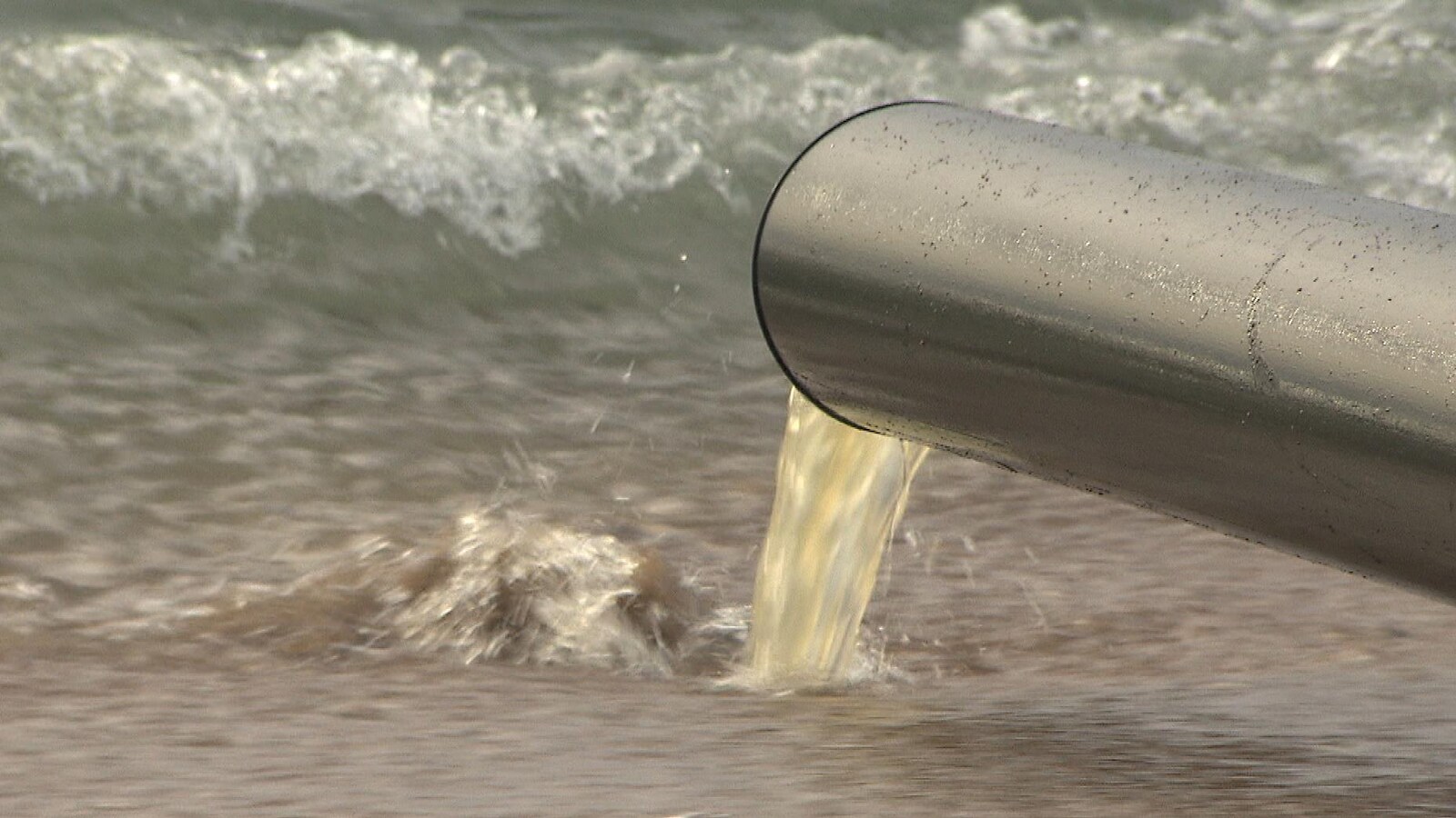 Un tuyau déverse de l'eau brunâtre dans le fleuve Saint-Laurent.