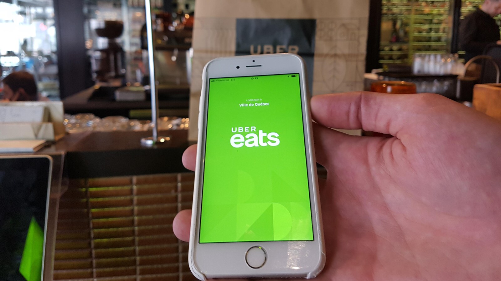 Une main tenant une téléphone cellulaire qui affiche l'application Uber eats