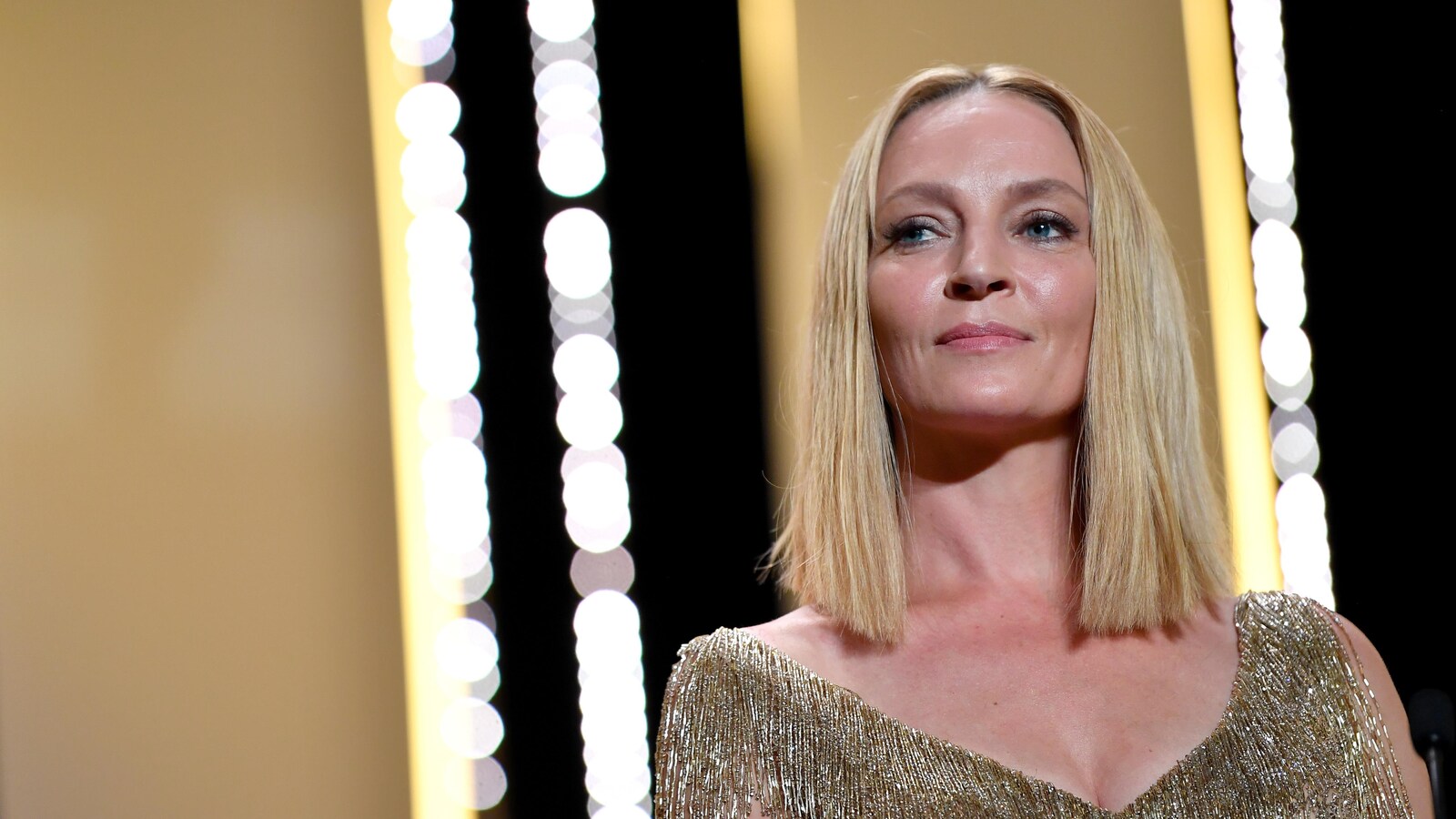 Uma Thurman, cheveux blonds aux épaules et portant une robe dorée lors de la cérémonie de fermeture du Festival de Cannes en 2017