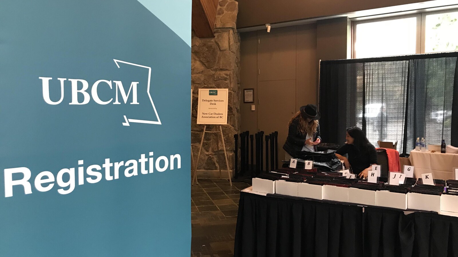 Affiche d'inscription au congrès dans un hall d'hôtel, avec la table d'accueil pour les congressistes et une personne qui est en train de s'inscrire.