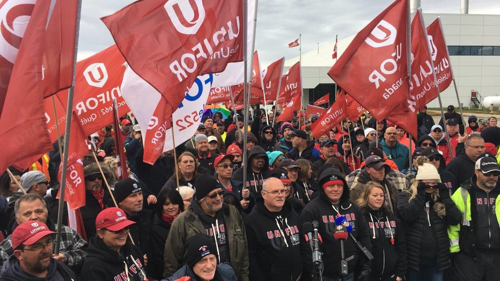Des manifestants agitant des drapeaux rouges d'Unifor.