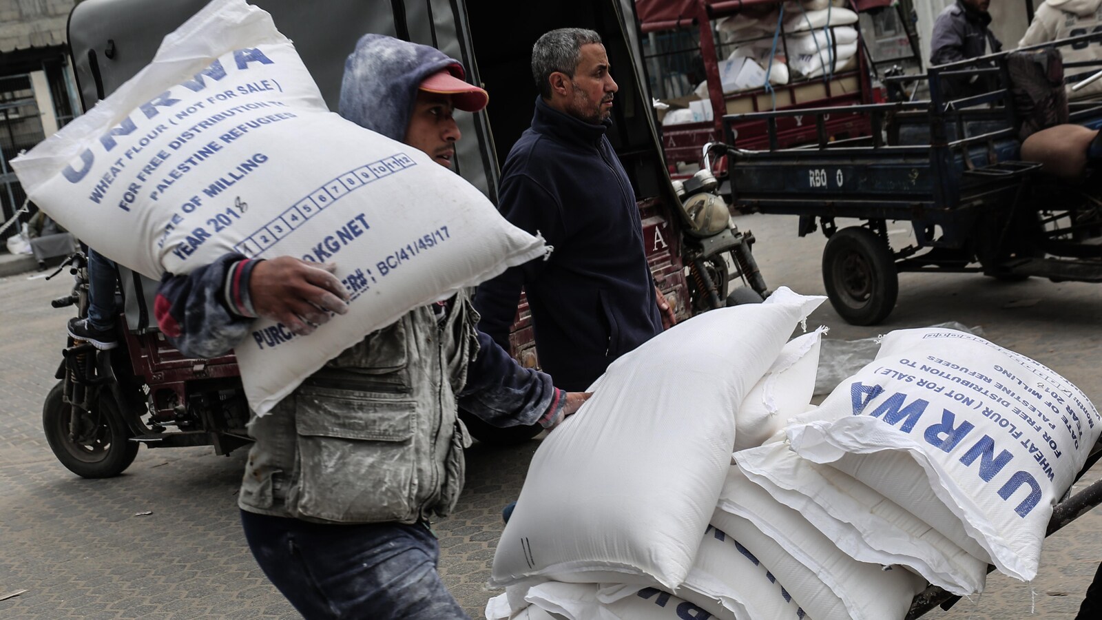 Un homme transporte un sac au logo de l'UNRWA sur son épaule.