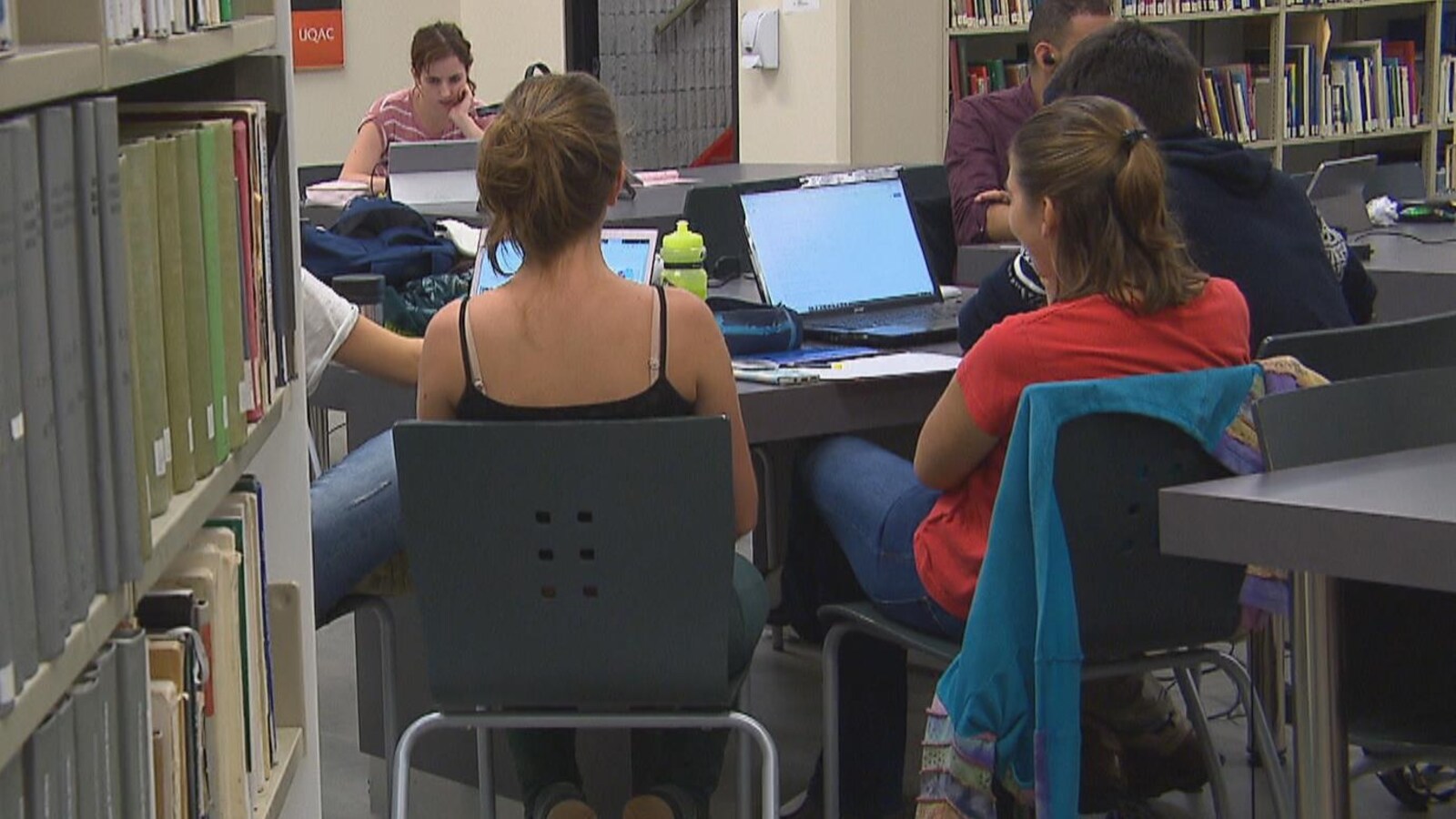 On voit des étudiants qui travaillent autour d'une table à la bibliothèque.