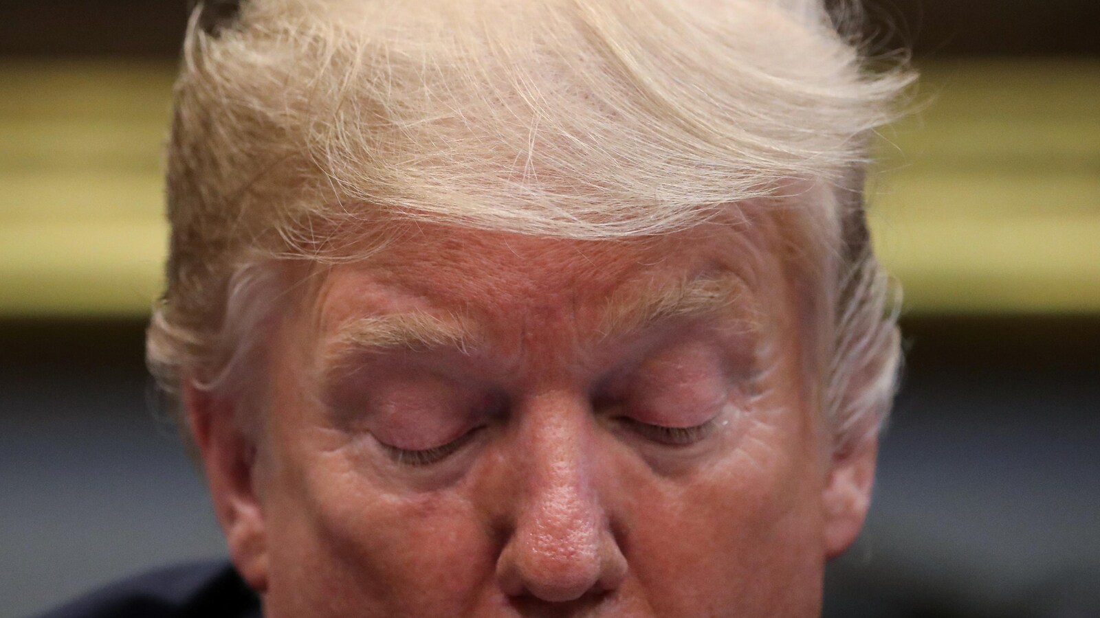 Plan rapproché de Donald Trump, qui a les yeux fermés.