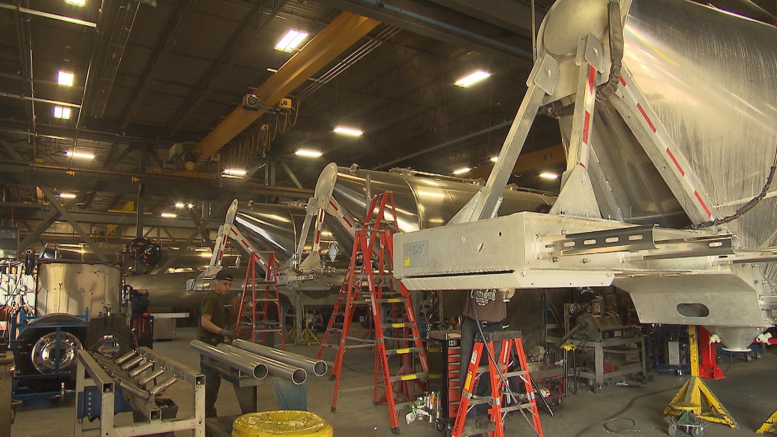 Une usine de fabrication de citernes en aluminium, où on voit des pièces et des ouvriers.