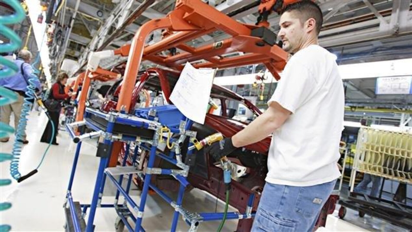 Un travailleur en contre-plongée travaille sur une Dodge Grand Caravan avec ses outils.