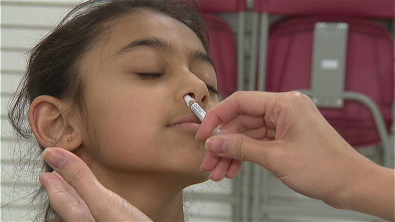 Une jeune fille reçoit un vaccin intranasal.
