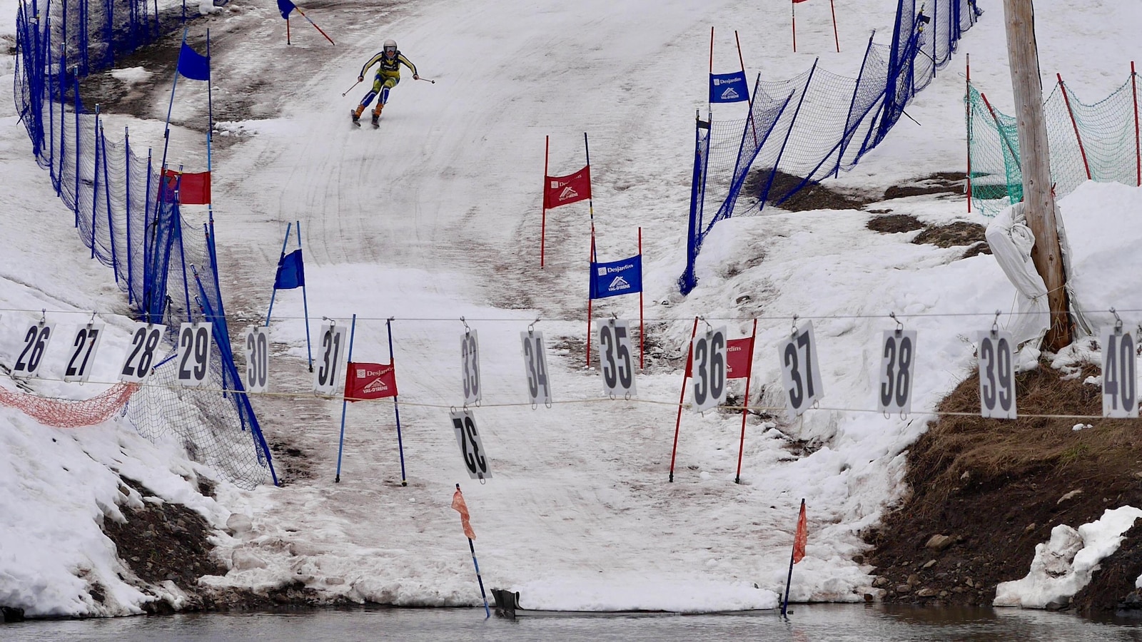 Un skieur descend une pente au pied de laquelle se trouve un lac.