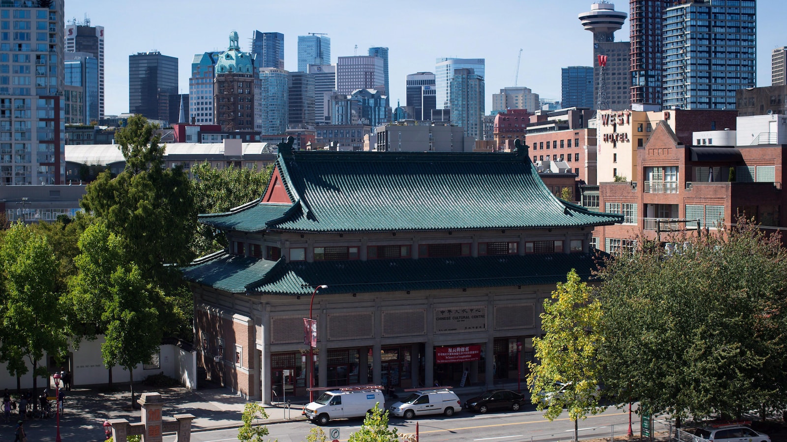 Un bâtiment à quelques étages vu devant des grandes tours à condominiums.