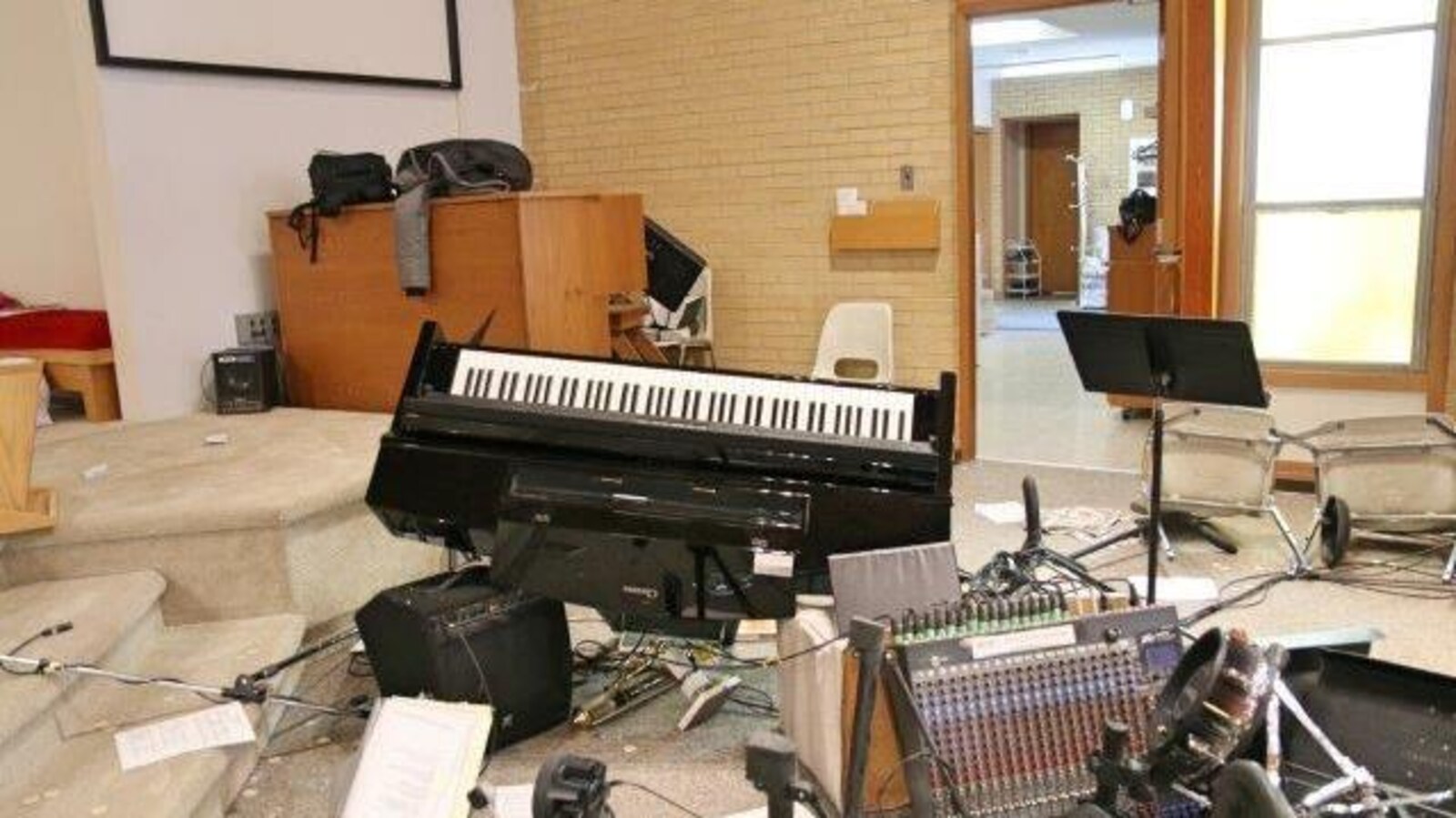 Un piano est à l'envers, l'équipement de musique est tombé et éparpillé