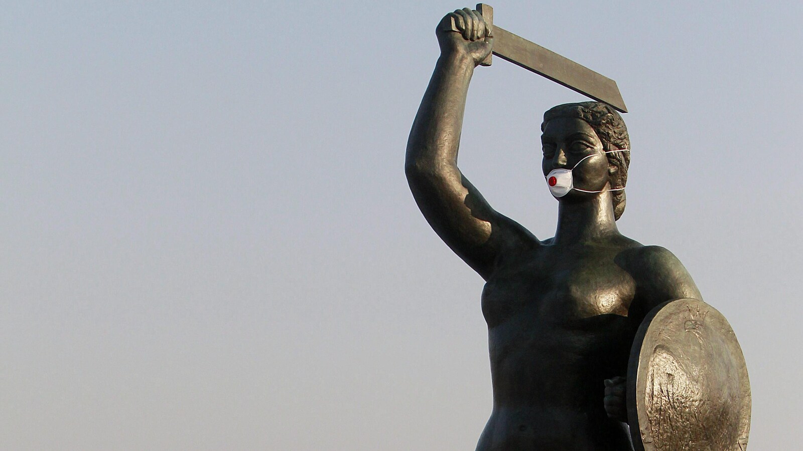Une statue de sirène avec une épée porte un masque.