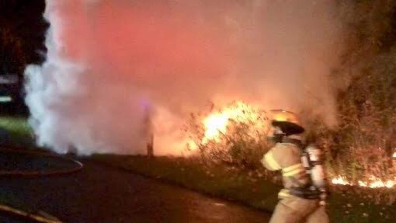Un pompier se dirigeant vers un véhicule en feu.