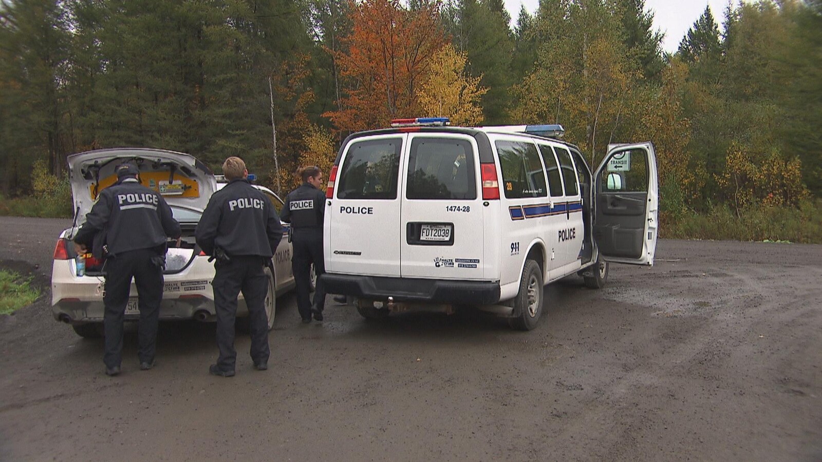 Des policiers et deux véhicules de police garés sur un chemin de campagne dans le secteur de Sainte-Marthe-du-Cap.