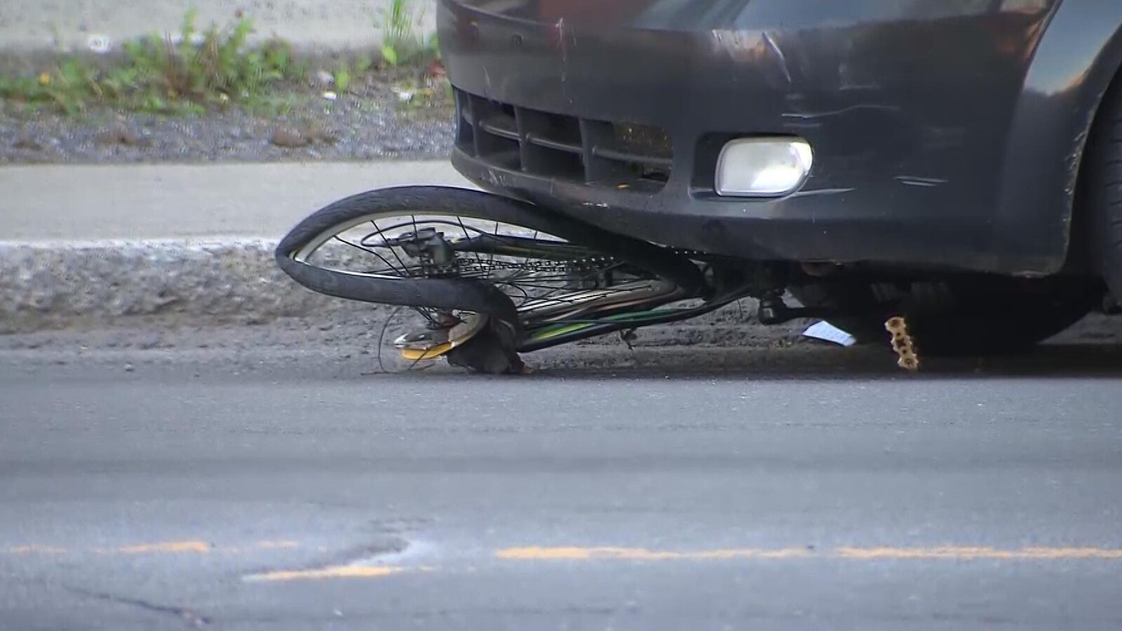 Le vélo est écrasé sous le devant de la voiture.