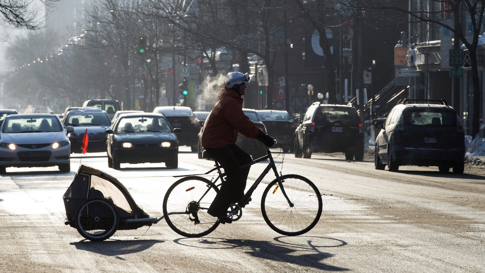 Un cycliste traverse une intersection dans des conditions hivernales, à Montréal.