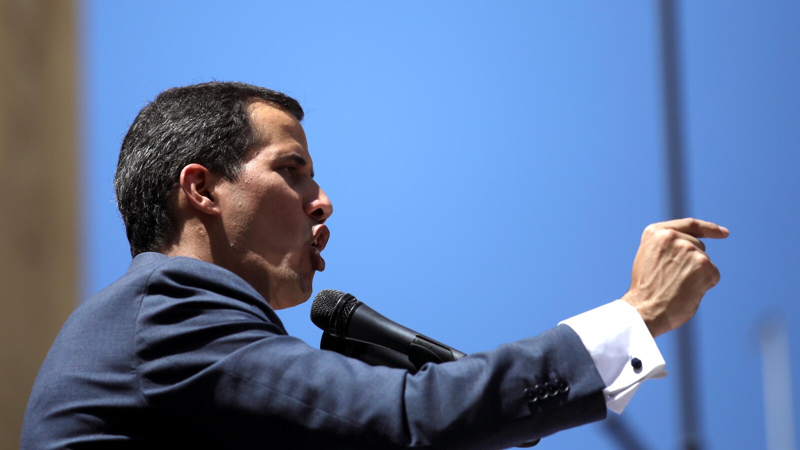 Juan Guaido parle au micro, le bras levé et le doigt pointé.