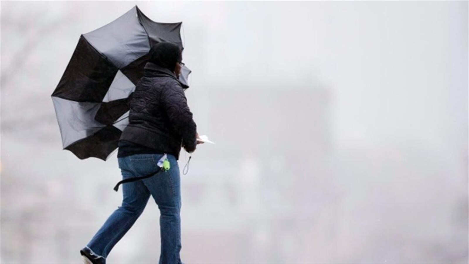 Une femme avec un parapluie retourné par le vent