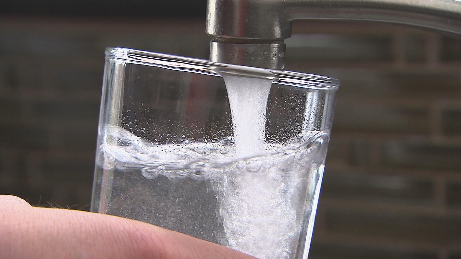 Un personne remplit un verre d'eau au robinet